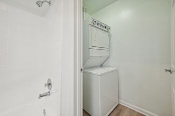 A white bathroom with a shower and a washer and dryer